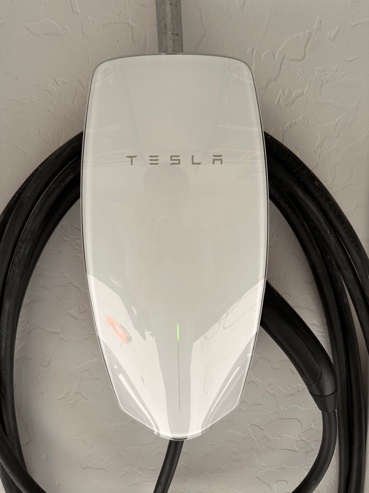 Wall-mounted Tesla EV charger installed in a Litchfield Park garage